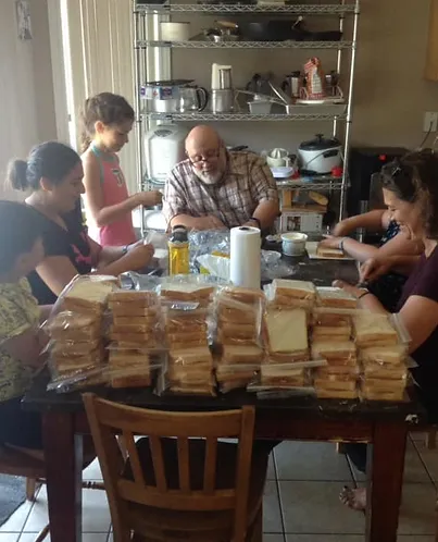 Group of people preparing and assembling sandwiches at a dining table